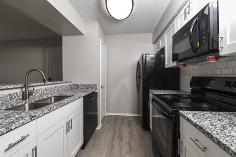 a kitchen with granite countertops and black appliances